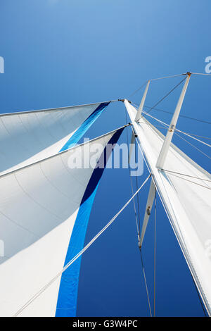 Segeln mit offenen Segeln auf einem Segelboot Mast auf einem blauen Himmel Stockfoto