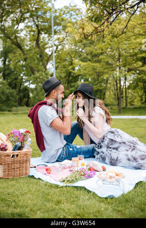Lächelnde junge Paar mit Picknick auf dem Rasen im park Stockfoto