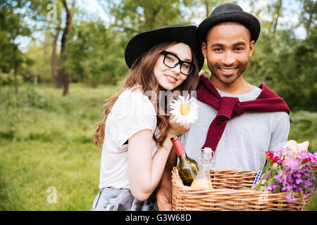 Porträt des jungen Brautpaares mit Korb voller Getränke, Lebensmittel und Blumen im Freien stehen Stockfoto