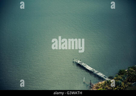 Einen tollen Blick auf ein altes angeschlagenen Dock in einem bläulich-grünen Fluss/See. Stockfoto