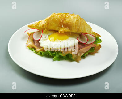 Sommer am Morgen das Frühstück Croissant gefüllt Rührei und Speck gebraten Stockfoto