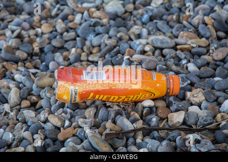 Eine Lucozade Flasche auf dem Boden an einem steinigen Strand in Norfolk. Stockfoto