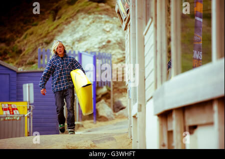 Stand Up Paddle Boarder tragen gelbe Tafel unter arm Stockfoto