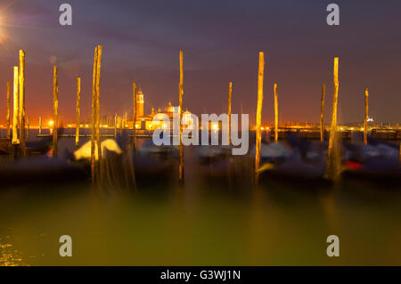 Abstraktes Bild von Gondeln festgemacht bis Holzmasten am Canal grande verschwommen durch Langzeitbelichtung und die Dünung des Wassers bei Nacht Venedig Stockfoto