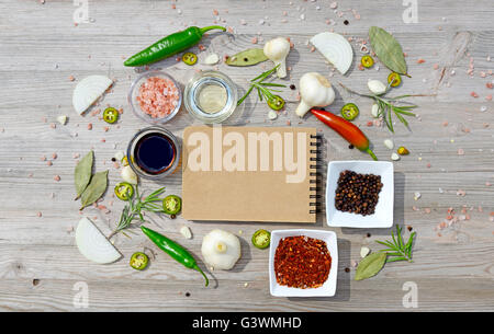 Leere Notebook für Notizen und Pfeffer, Lorbeer, Rosmarin, Zwiebeln, Salz, Olivenöl, Soja-Sauce auf einem Holztisch. Ansicht von oben Stockfoto