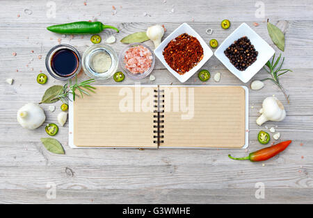 Leere offene Notebook für Notizen und Pfeffer, Lorbeer, Rosmarin, Zwiebeln, Salz, Olivenöl, Soja-Sauce auf einem Holztisch Stockfoto