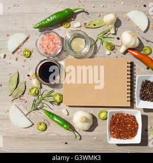 Leere offene Notebook für Notizen und Pfeffer, Lorbeer, Rosmarin, Zwiebeln, Salz, Olivenöl, Soja-Sauce auf einem Holztisch Stockfoto