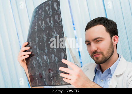 Closeup Portrait des Pflegepersonals intellektuellen Mann mit weißen Laborkittel Gehirn Röntgen Röntgenbild, Ct-Scan, mri, Klinik-Office-Hintergrund zu betrachten. Radiologie Stockfoto
