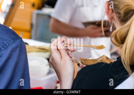 Attraktive junge blonde Frau Straße Essen genießen. Stockfoto