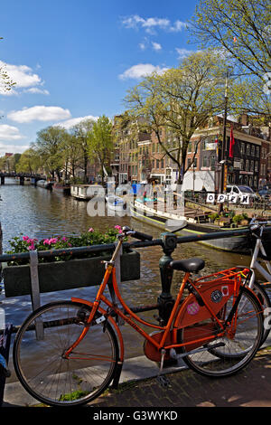 Rotes Fahrrad auf einer Brücke über die Prinsengracht in der Innenstadt von Amsterdam, Niederlande. Stockfoto