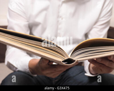 Gut aussehender Mann, einem alten Buch auf dem sofa Stockfoto