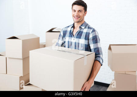 Lächelnd, glücklichen, gut aussehender Mann mit Kartons in neue Wohnung Stockfoto