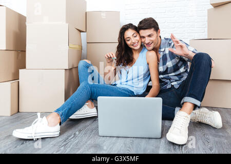 Junge Brautpaar am Boden bewegt sich in ein neues Haus oder eine Wohnung flach mit Computer laptop Stockfoto