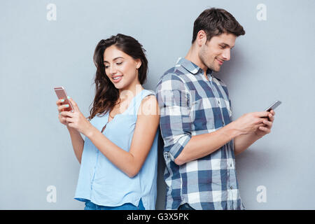 Glückliches Paar Smartphone auf grauem Hintergrund isoliert betrachten Stockfoto