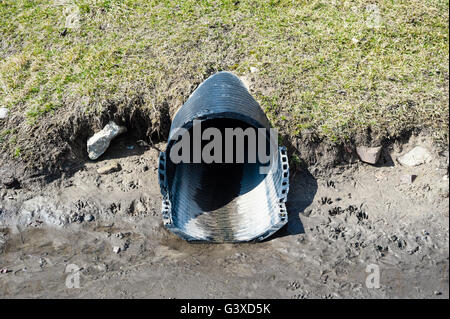 Schmutzigen schwarzen Kunststoffrohr aus Rasen in nassen Schlamm. Stockfoto