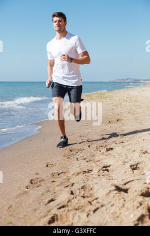 Attraktive junge Sportler Joggen am Strand am Morgen Stockfoto