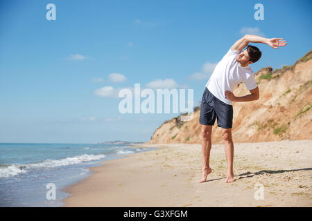 Volle Länge des attraktiven jungen Sportler stehen und Training am Strand Stockfoto