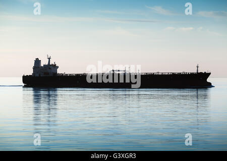 Große industrielle Tanker Schiff geht auf noch Meerwasser, Silhouette Foto, natürlichen Gegenlicht Effekt Stockfoto