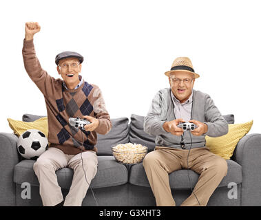 2 Senioren spielen Fußball-Videospiel sitzen auf einer Couch isoliert auf weißem Hintergrund Stockfoto