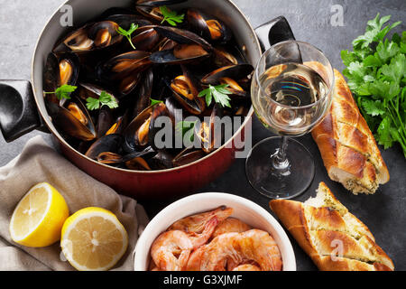 Muscheln, Garnelen und Weißwein auf Steintisch Stockfoto