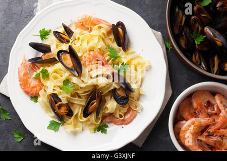 Pasta mit Meeresfrüchten am Steintisch. Muscheln und Garnelen. Ansicht von oben Stockfoto