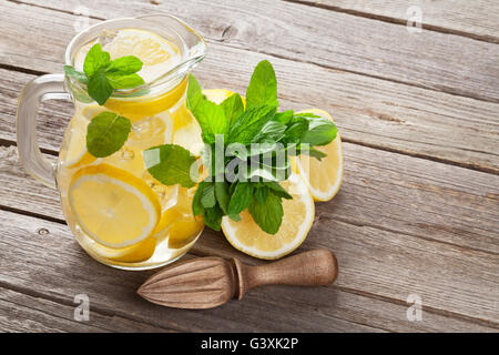 Limonade Krug mit Zitrone, Minze und Eis am Gartentisch Stockfoto