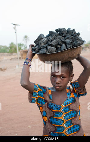 Mali, Mädchen tragen Holzkohle in Schüssel auf den Kopf, was sie als Kochbrennstoff verkauft Stockfoto