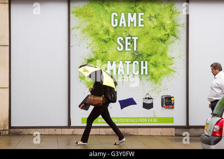 Wimbledon London, UK. 16. Juni 2016. Fußgänger in Regenschirme bergende gehen vorbei an eine große Tennis-Plakat mit den Worten "Spiel und Spiel" als Wimbledon bereitet Gastgeber der 2016 Rasenplatz Tennis Championships Credit: Amer Ghazzal/Alamy Live-Nachrichten Stockfoto