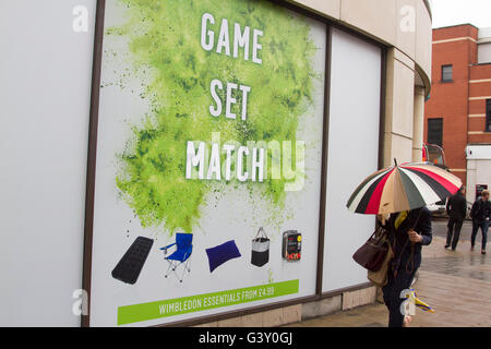 Wimbledon London, UK. 16. Juni 2016. Fußgänger in Regenschirme bergende gehen vorbei an eine große Tennis-Plakat mit den Worten "Spiel und Spiel" als Wimbledon bereitet Gastgeber der 2016 Rasenplatz Tennis Championships Credit: Amer Ghazzal/Alamy Live-Nachrichten Stockfoto