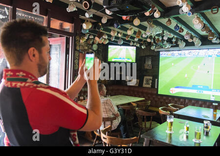 Llansaint, Carmarthenshire, Wales, UK. 16. Juni 2016.  Aus Wales und England-Fans sehen Fußballspiel England gegen Wales in Kings Arms Pub im Dorf von Llansaint,Carmarthenshire,Wales.England 2: 1 gewinnen. Bildnachweis: Paul Quayle/Alamy Live News, nimmt walisischen Fan Foto vom Bildschirm mit seiner Kamera-Handy, wenn Wales 1: 0 gewannen. Stockfoto