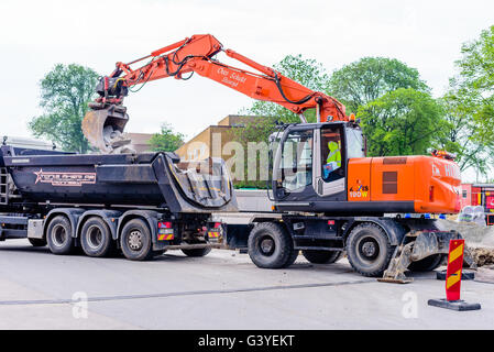 Karlskrona, Schweden - 16. Juni 2016: Orange Hitachi Zaxis 190W Bagger Graben aus Steinen aus einem Loch auf einem Parkplatz bei Potth Stockfoto