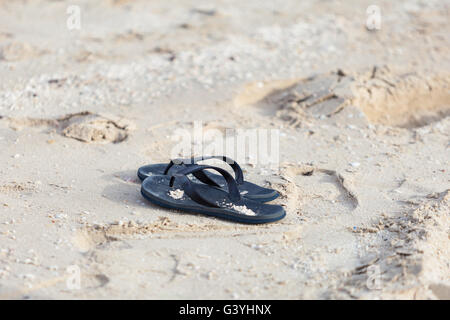 Flip Flops, Tangas, Folien, aufgegeben am Sandstrand am Meer Stockfoto