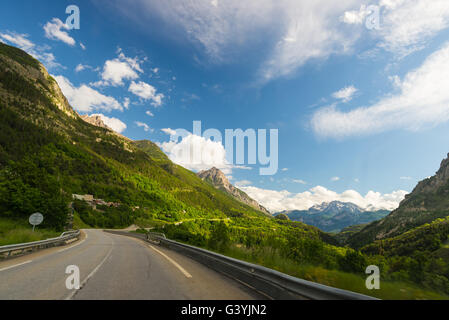 Befestigte zwei Lane Straße Kreuzung Berge und Wald in malerischen Alpenlandschaft und stimmungsvoller Himmel. Panoramablick vom Auto montiert kam Stockfoto