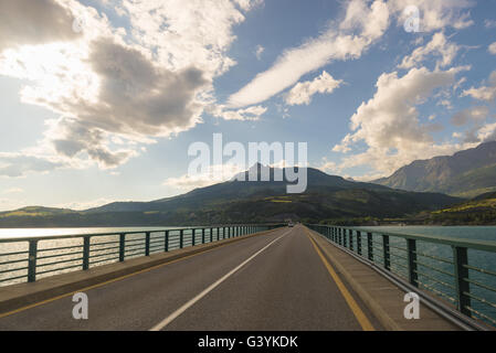 Zwei Fahrbahn auf der Brücke Kreuzung See landschaftlich und stimmungsvoller Himmel gepflastert. Panoramablick vom Auto montierten Kamera. Sommer-Anzeige Stockfoto