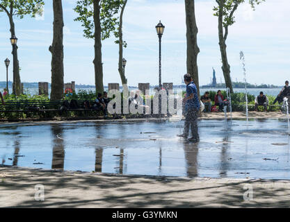 Jungs im Teenageralter läuft durch einen öffentlichen Brunnen und Flickschusterei in Battery Park, New York im Sommer kühl zu halten. Stockfoto