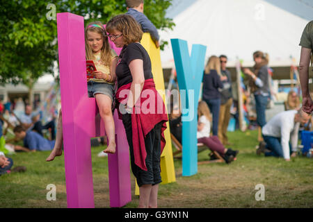 Eine Mutter und Kind Tochter Mädchen besuchen Besucher amüsieren sich mit eines der großen Zeichen auf dem Heu-Festival der Literatur und Kunst, Hay on Wye, Powys, Wales UK, Mai 2016 Stockfoto