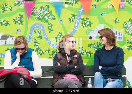 Drei Frauen besucht Besucher amüsieren sich in die warmen Sonnenstrahlen am Hay Festival der Literatur und Kunst, Hay on Wye, Powys, Wales UK, Mai 2016 Stockfoto