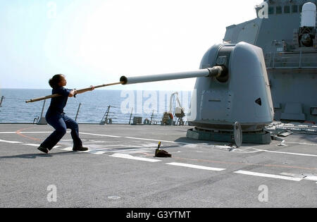 Ein "Gunners" Mate reinigt den Lauf der Mark 45 auf dem Lenkflugkörper Zerstörer USS Trichter. Stockfoto