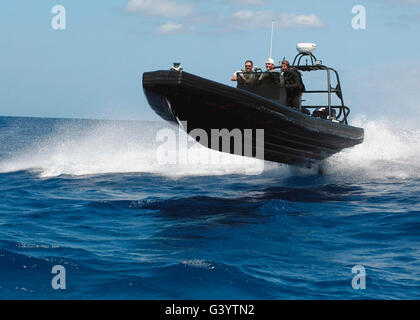 US Navy Matrosen betreiben eine neun Meter starre Hull Inflatable Boat mit hoher Geschwindigkeit. Stockfoto