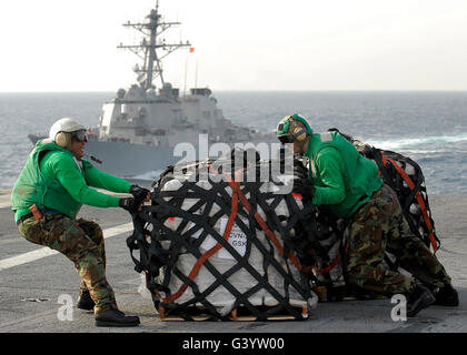 Matrosen bewegen Versorgungsmaterialien auf dem Flugdeck an Bord der USS Abraham Lincoln. Stockfoto