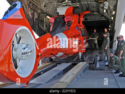 Ein Aircrew lädt einen Coast Guard HH-65 Dolphin-Helikopter auf einer c-17 Globemaster III. Stockfoto