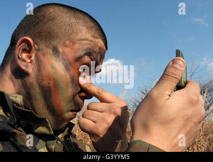 Ein Soldat Gesicht Lackieren vor Beginn der vierteljährlichen Air Base Defense Training, Misawa Air Base, Japan. Stockfoto