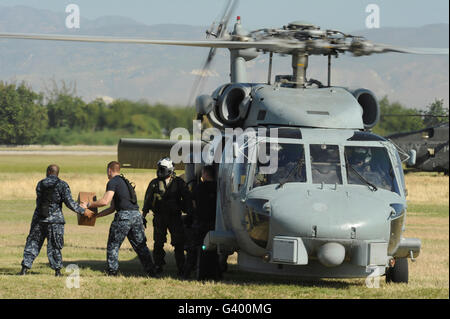 US Navy Matrosen laden Hilfsgüter auf eine Marine HH-60 Pave Hawk-Hubschrauber. Stockfoto