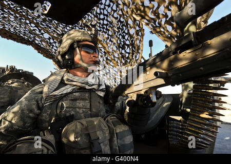 US Armee-Spezialist bietet hinten Sicherheit in einem gepanzerten Fahrzeug von Stryker. Stockfoto