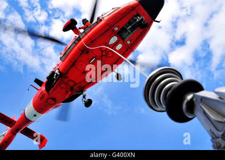 Chief Petty Officer sieht aus der Tür ein HH-65 Dolphin-Helikopter. Stockfoto