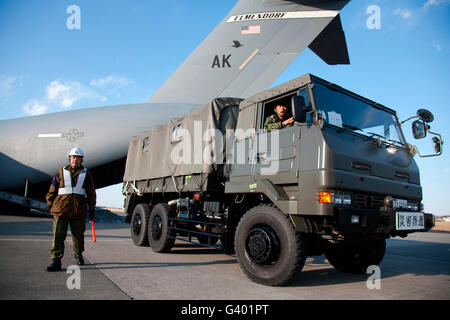 Ein japanischer Soldat Marschälle Fahrzeuge aus einer c-17 Globemaster III. Stockfoto