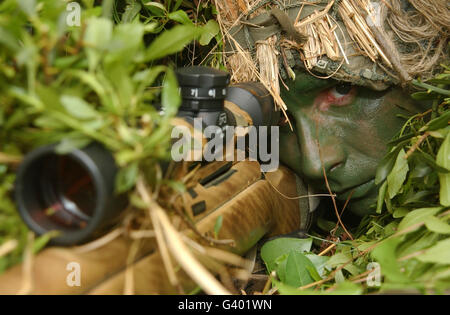 Ein Scharfschütze im Ghillie-Anzug gekleidet Stiele seinen Feind Stockfoto