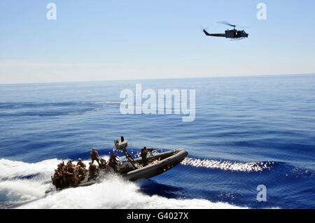 Ein US-Marine UH-1N Huey Hubschrauber bietet Deckung für US-Marines auf einem Festrumpf-Schlauchboot. Stockfoto