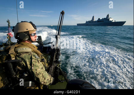 Kanonier mans eine.50 Kaliber Maschinengewehr auf einem Fließgewässer Boot. Stockfoto