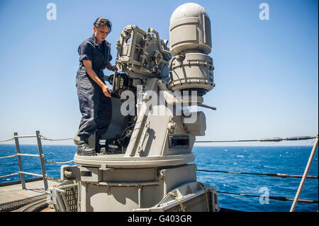 Seaman führt Wartungsarbeiten an einer Mark 38 MOD 2 25mm Maschinengewehr / Stockfoto